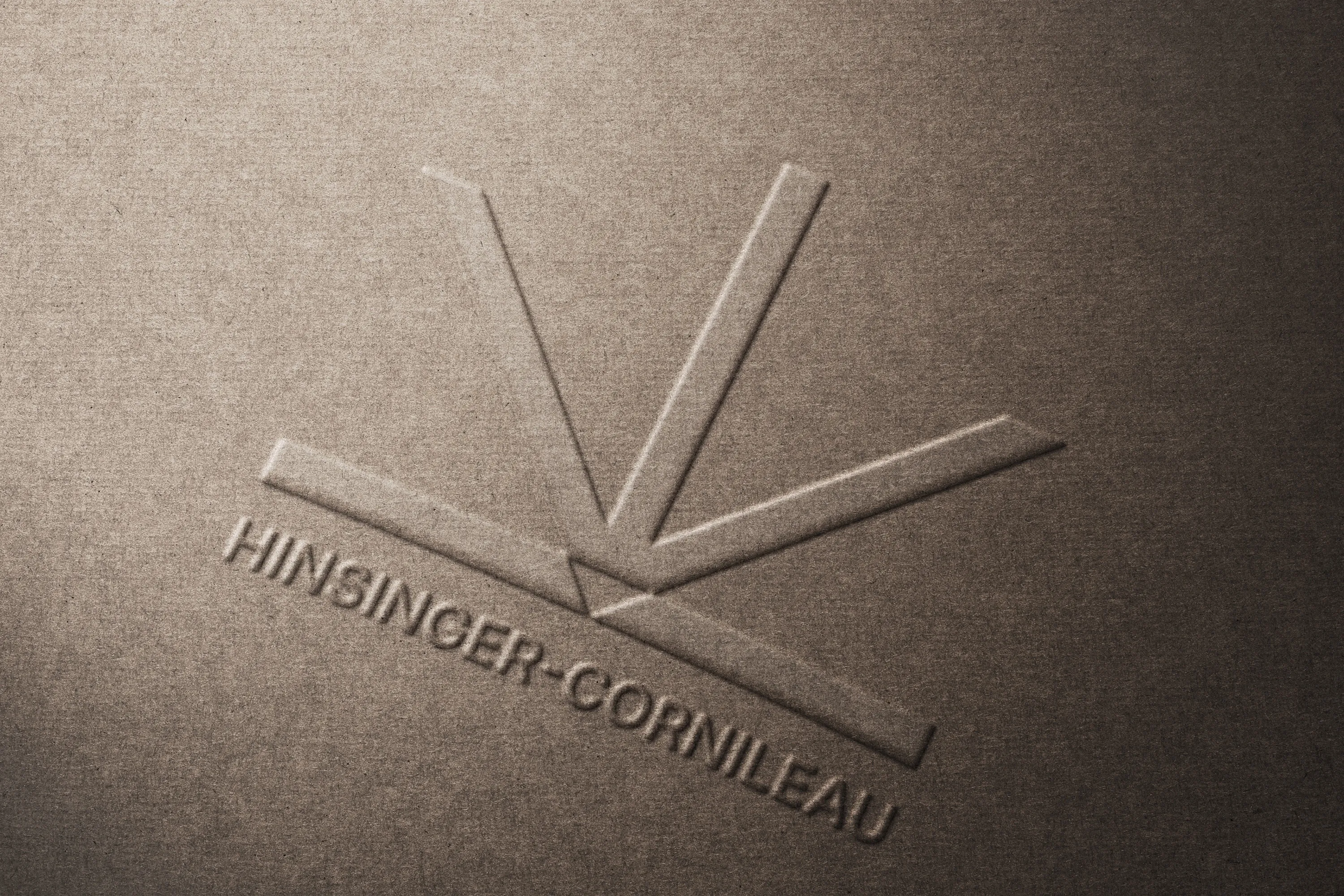 Le logo Hinsinger-Cornileau embossé sur un papier kraft : un éventail de traits convergents au-dessus du nom